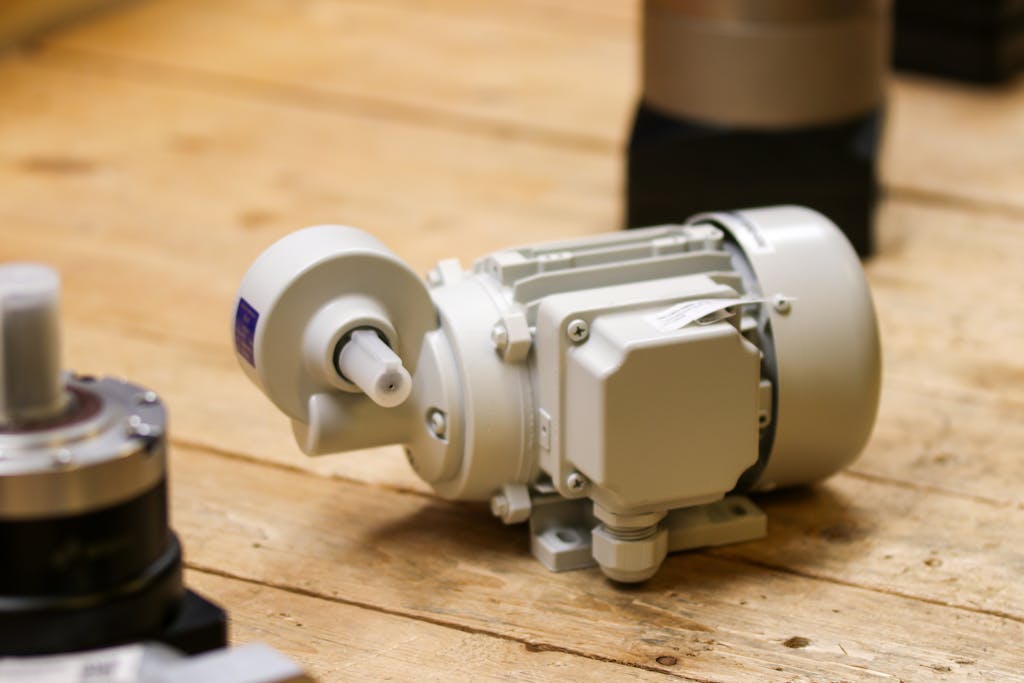 Close-up of a white industrial motor placed on a wooden surface inside a workshop.