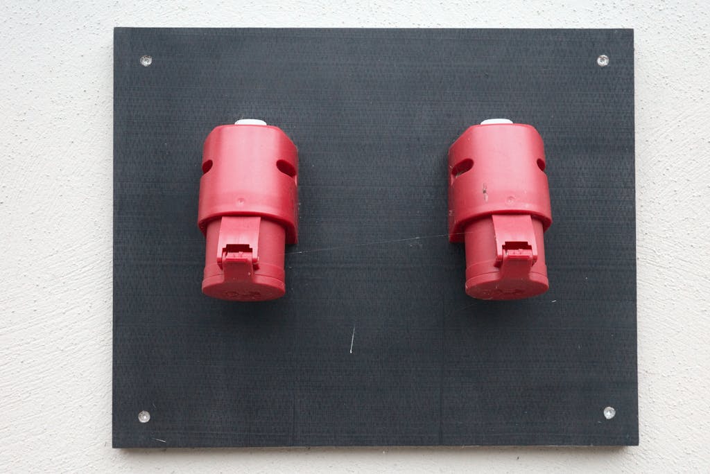 Image of two red industrial electrical connectors mounted on a wall.
