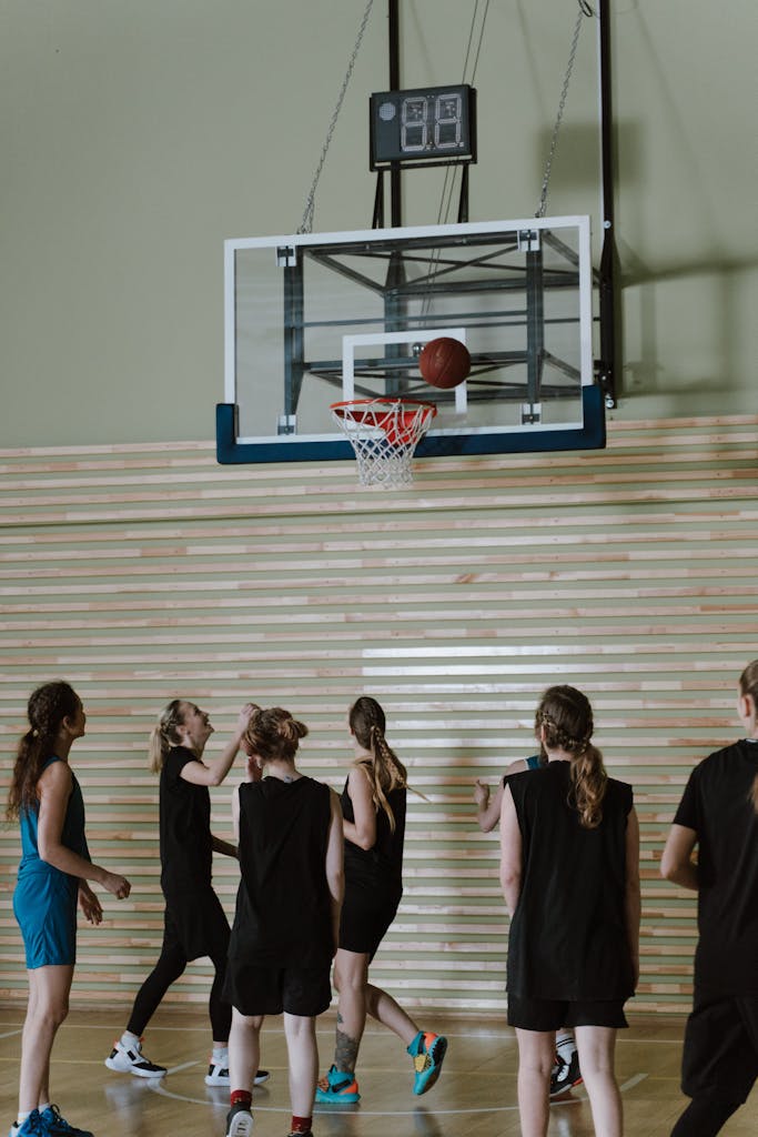 A team of young women playing basketball indoors, aiming for the hoop.